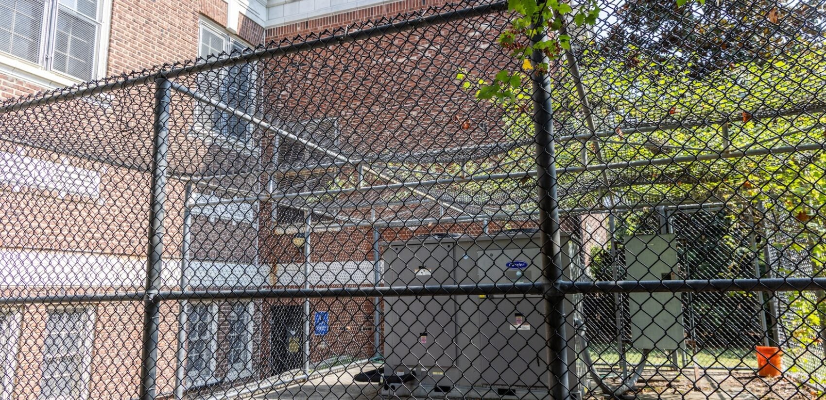 An HVAC system outside in a fenced area outside of Oak Lane Library