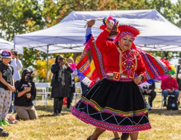 A performer wearing traditional clothing performs at Indigenous Peoples' Day