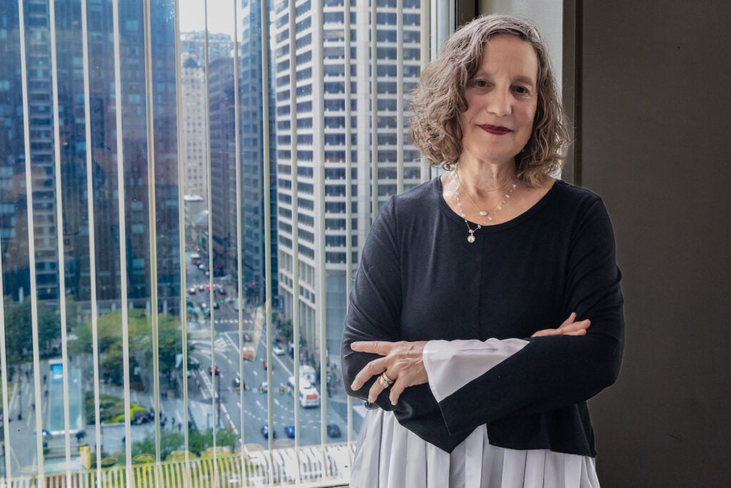 Elizabeth Hersh poses for a photo in front of a window looking out on Center City Philadelphia