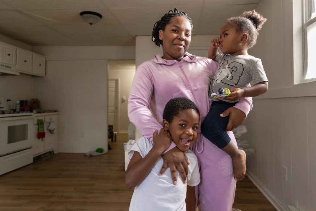 Lachnee Nelson poses for a photo with her two children in her apartment
