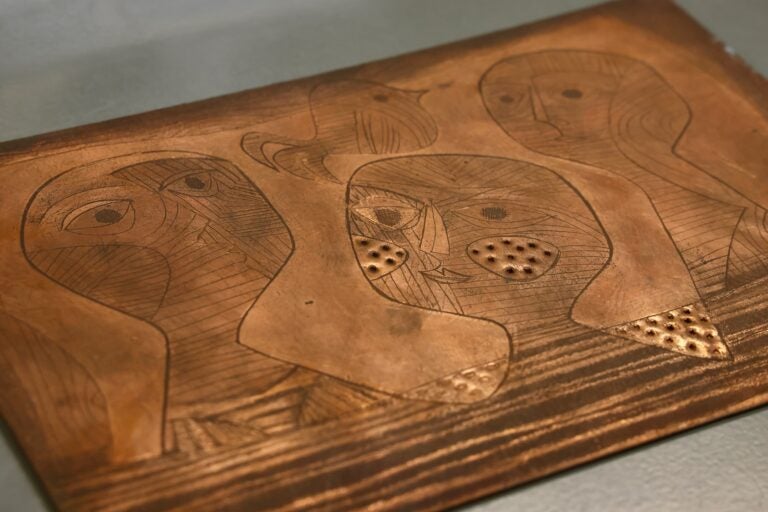 A print plate made by textile artist Laura Jean Allen shows three abstract faces