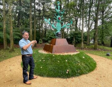 Salvador Jiménez-Flores poses for a photo near his sculpture