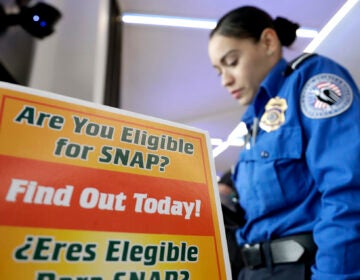 A police woman in front of a sign for SNAP eligibility