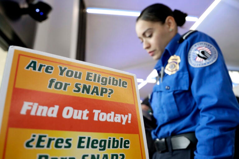A police woman in front of a sign for SNAP eligibility