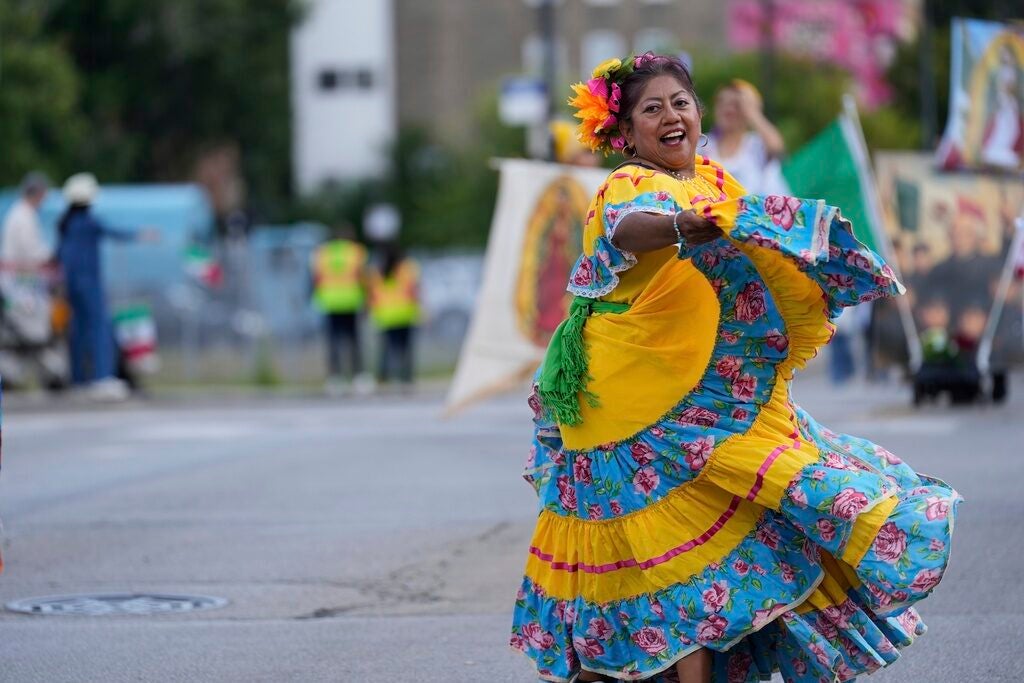 A woman dances in a blue and yellow dress during a Mexican Independence Day parade in Chicago