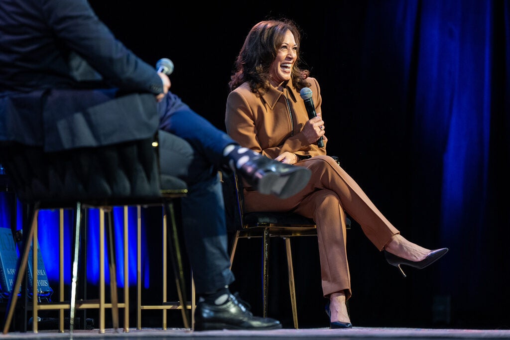 Former Vice President Kamala Harris sits in a chair, smiling while discussing her latest book