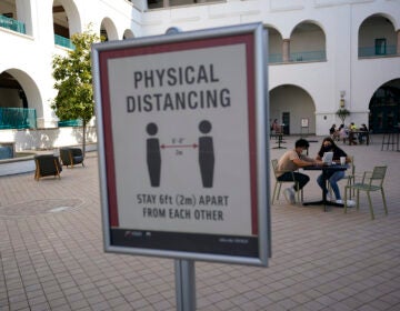 People sit at tables at San Diego State University Wednesday, Sept. 2, 2020, in San Diego. San Diego State University on Wednesday halted in-person classes for a month after dozens of students were infected with the coronavirus. (AP Photo/Gregory Bull)