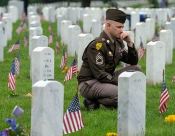 A member of the Army keels by a tombstone in Section 60 of Arlington National Cemetery