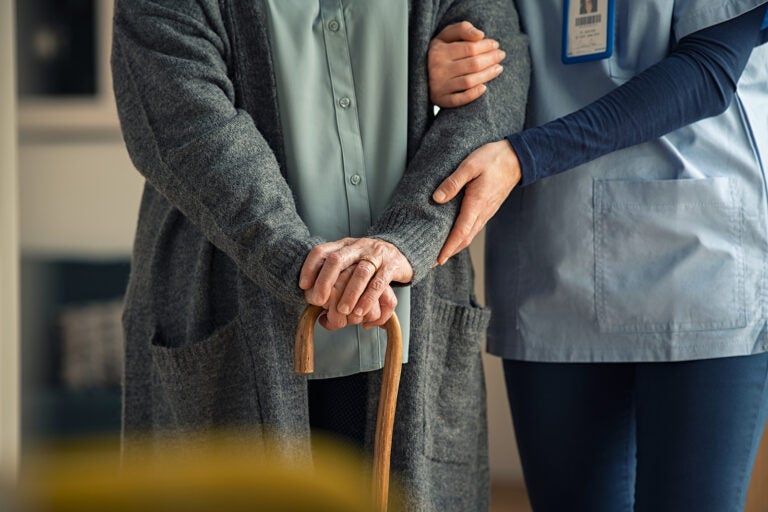Close up hands of caregiver doctor helping old woman at clinic.