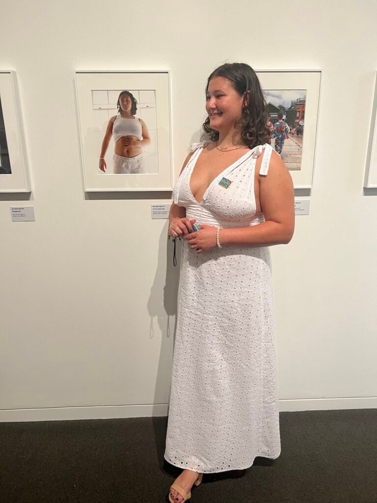 Elodie Hekimian-Brogan stands by a photographed self-portrait titled "Reconnecting With Innocence" at a reception at the Getty Villa Museum in Los Angeles. Her photograph was displayed at the art museum in 2022 for six months. (Courtesy of Elodie Hekimian-Brogan)
