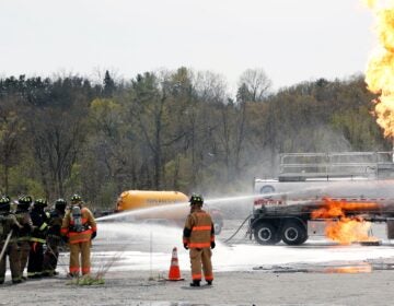 Firefighters spray fire suppressant foam to douse flames on a tanker truck