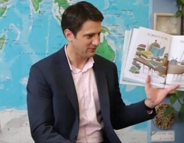 Justin Lee Smith holding up a book in a classroom