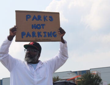 A man protesting a proposed Children's Hospital of Philadelphia parking lot holds a sign that reads 
