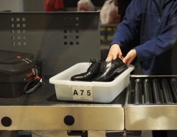 An air traveler puts their shoes in a bin at an airport security checkpoint