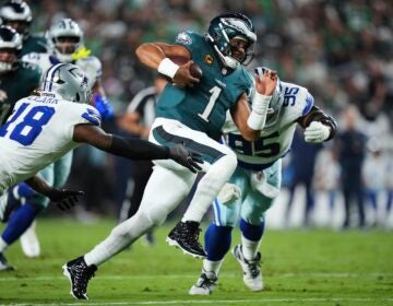 Philadelphia Eagles quarterback Jalen Hurts (1) runs the ball as Dallas Cowboys' Damone Clark (18) and Kenny Clark (95) attempt to make the stop in the first half of an NFL football game Thursday, Sept. 4, 2025, in Philadelphia