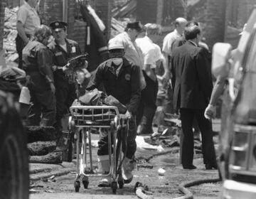 A worker transports the remains of a body found within the debris of the house of the MOVE compound in West Philadelphia