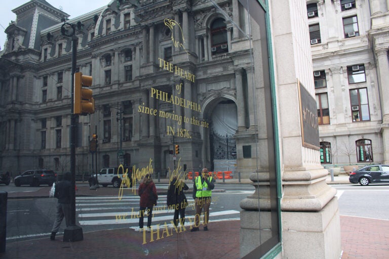 The window of the Center City Macy's shows people walking by