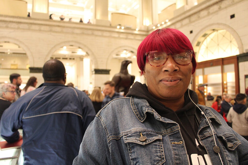 A woman with red hair speaks about organ concerts at the Wanamaker building in Philadelphia
