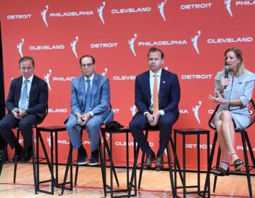 Various officials sitting on stools on a stage during a press conference